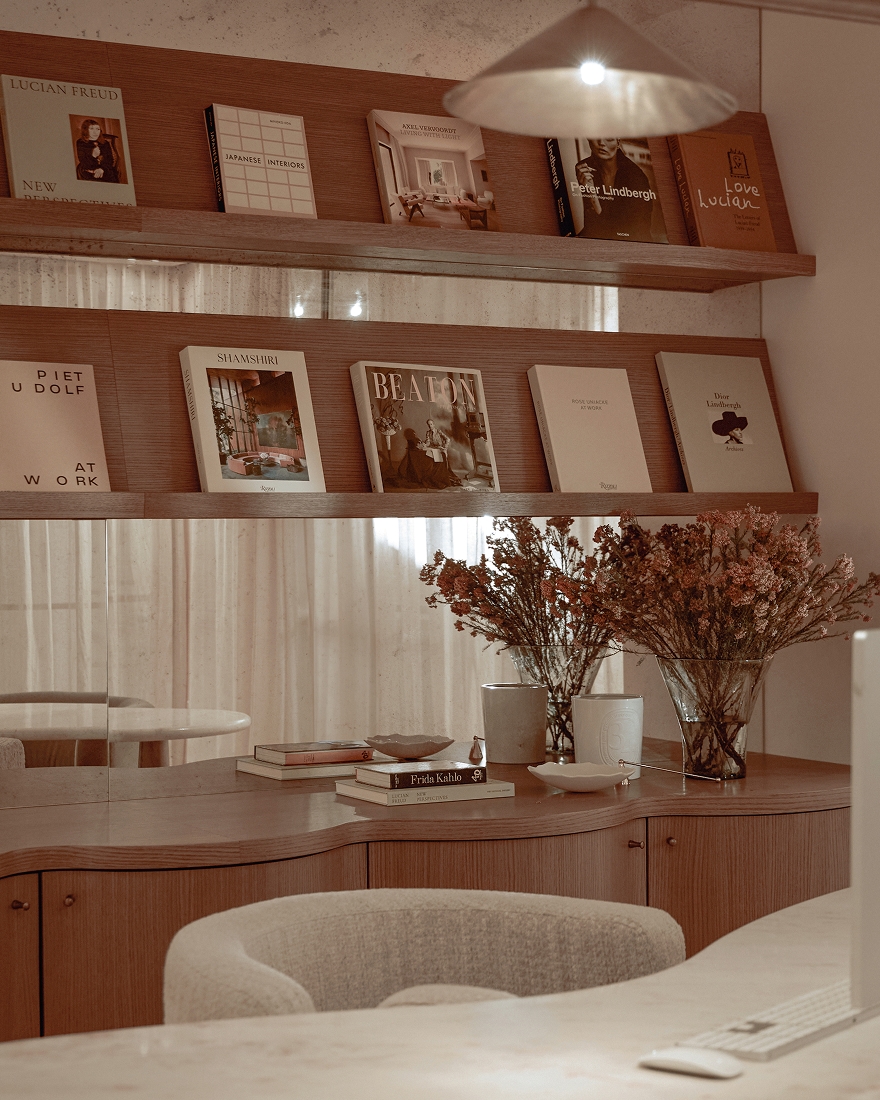 Wooden shelving with design books, floral arrangements, and decorative objects in a warm contemporary interior