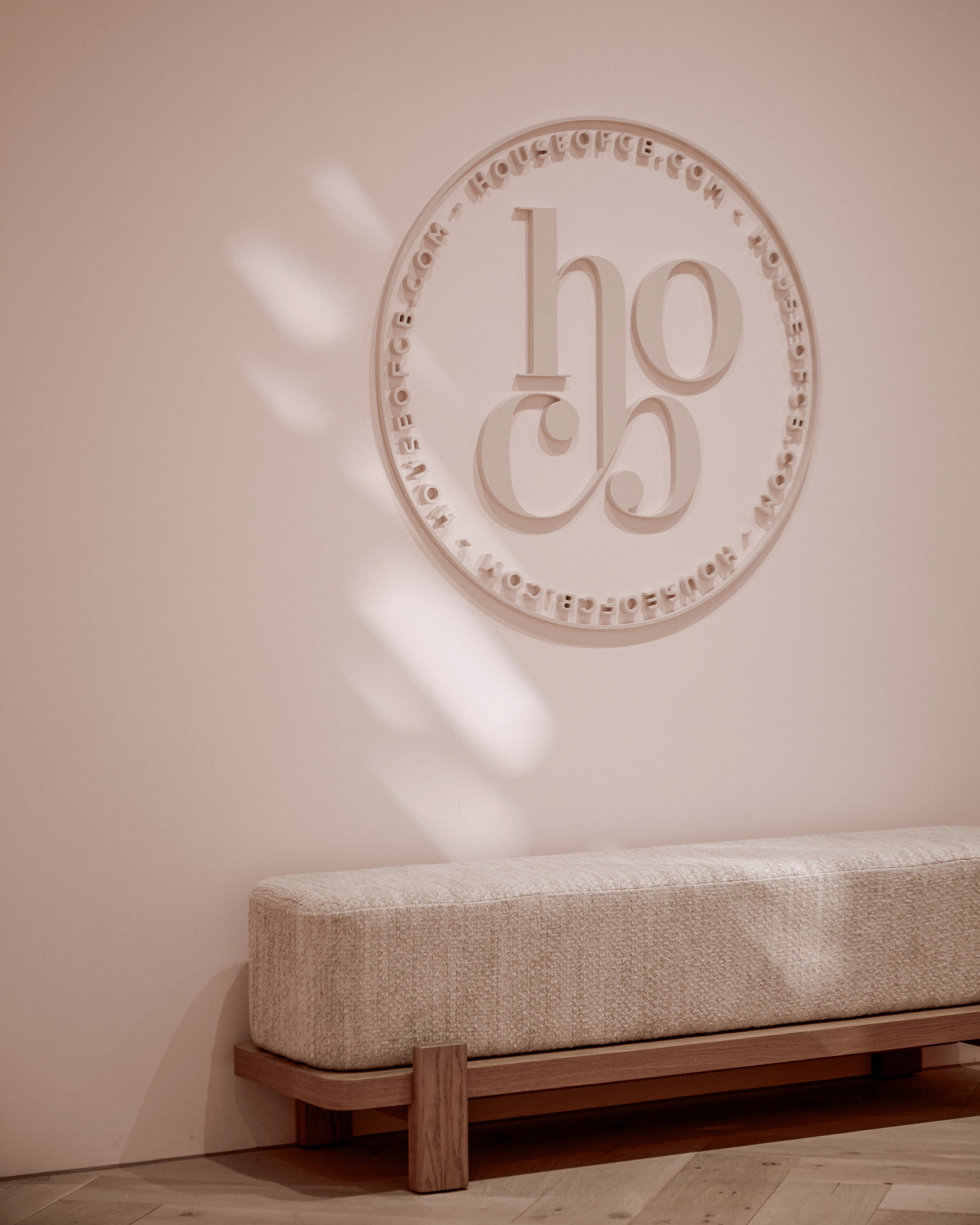Upholstered bench beneath a decorative wall emblem in a softly lit contemporary interior