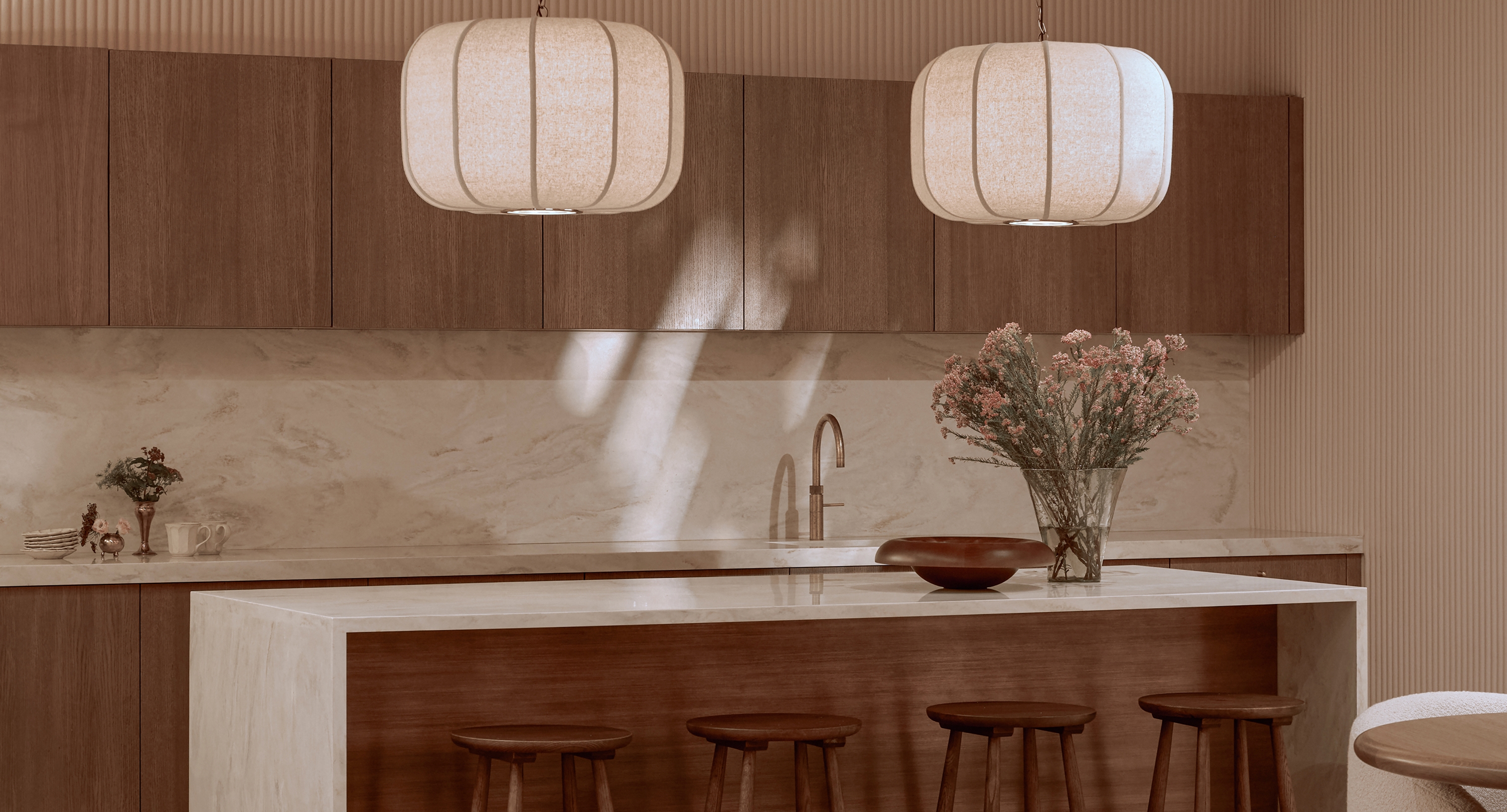Modern kitchen with marble island, wooden cabinetry, pendant lighting, and floral arrangement