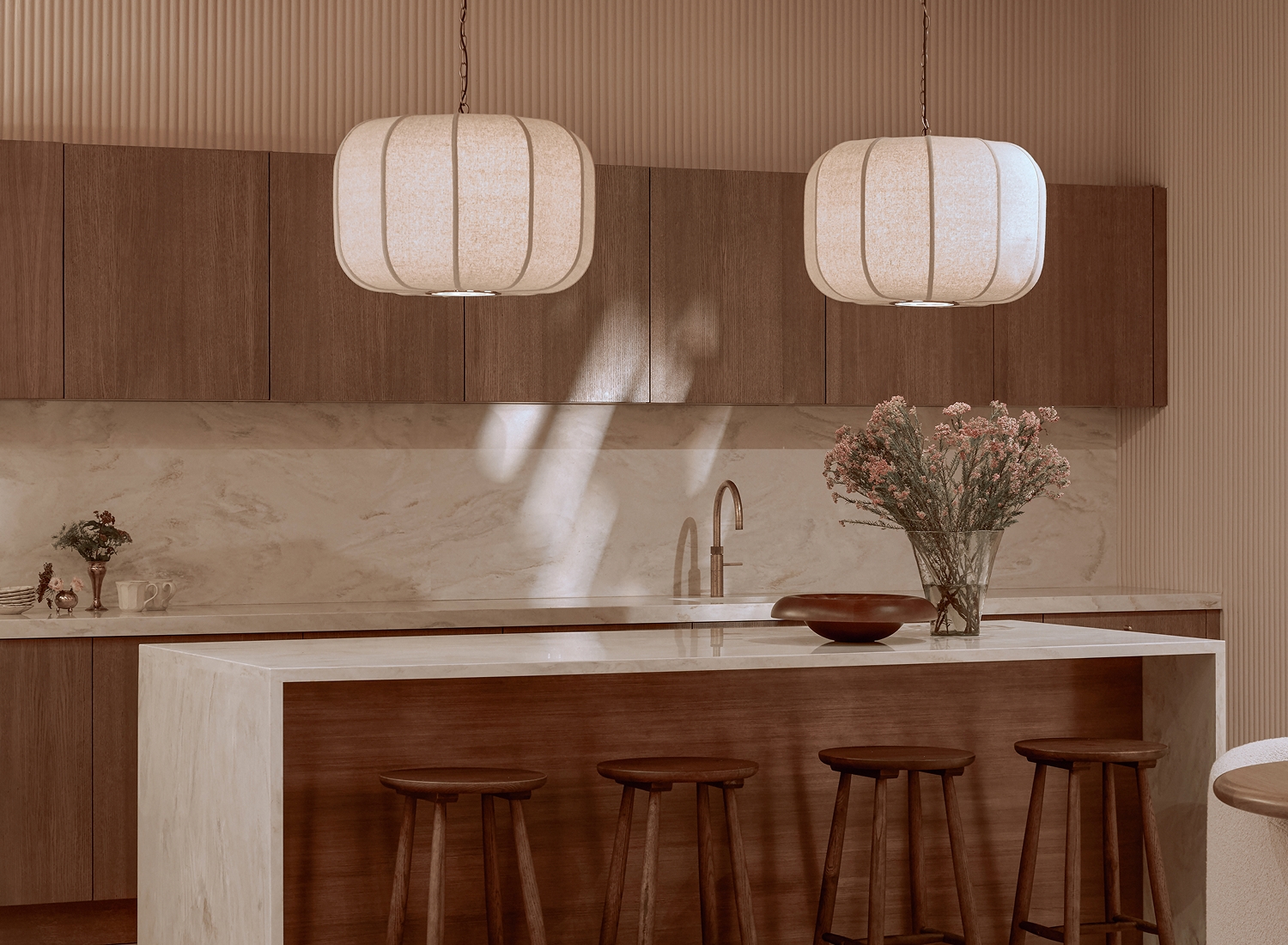 Modern kitchen with marble island, wooden cabinetry, pendant lighting, and floral arrangement