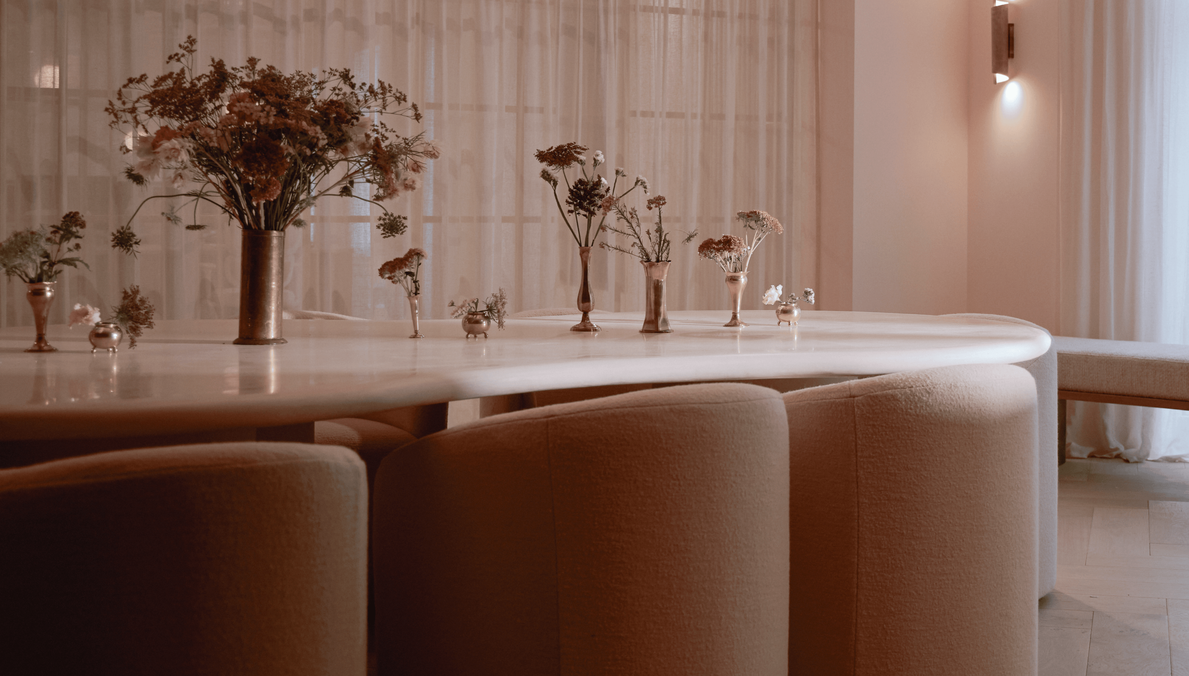 White marble dining table with vases of flowers and beige upholstered chairs