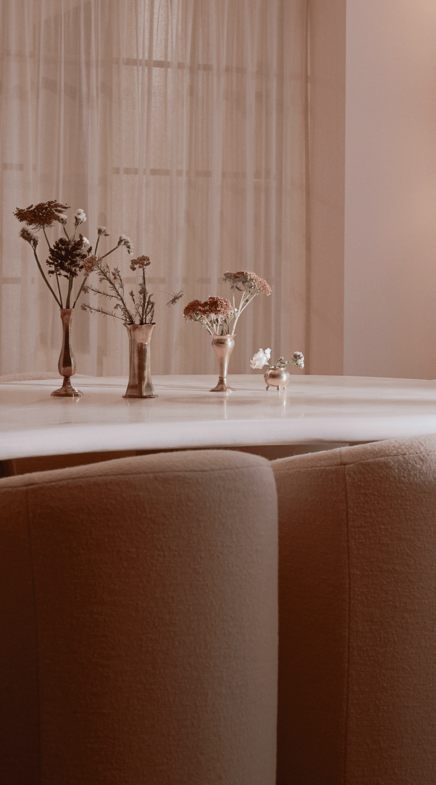 White marble dining table with vases of flowers and beige upholstered chairs